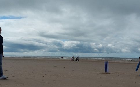 Young people playing cricket on Blackpool beach.